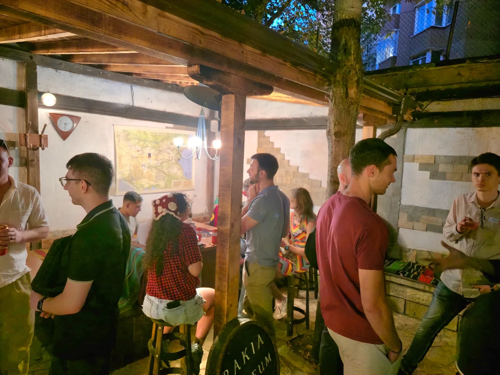 Community icebreaker gathering in Sofia under the wooden pergola at Rakia Museum